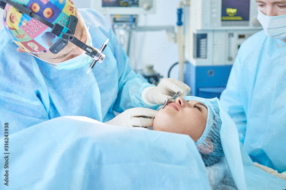 Several doctors surrounding patient on operation table during their work. Team surgeons at work in operating room
