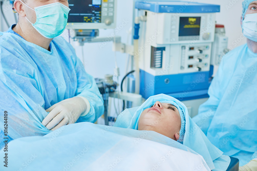 Several doctors surrounding patient on operation table during their work. Team surgeons at work in operating room Several doctors surrounding patient on operation table during their work. Team surgeons at work in operating room
