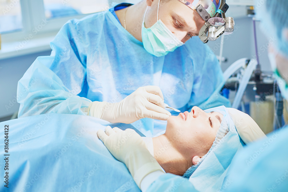 Several doctors surrounding patient on operation table during their work. Team surgeons at work in operating room Several doctors surrounding patient on operation table during their work. Team surgeons at work in operating room