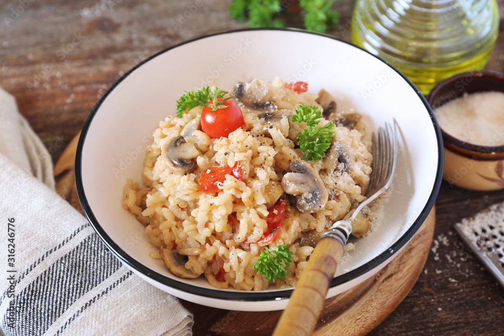 Italian cuisine. Plate of mushroom risotto with cherry tomatoes and parmesan cheese Italian cuisine. Plate of mushroom risotto with cherry tomatoes and parmesan cheese