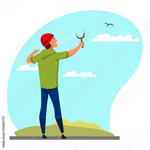 Teenager boy aiming with slingshot at bird in sky