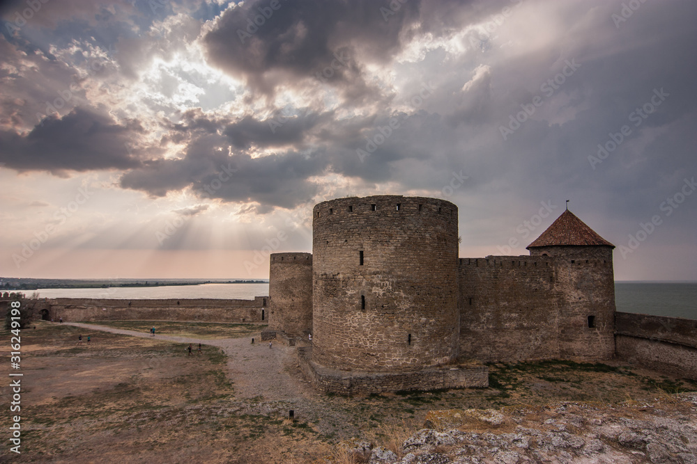 Akkerman fortress over dramatic sky in sunset sunrays. Bilhorod-Dnistrovskyi, Odesa oblast, Ukraine