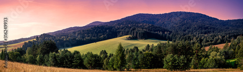 Majestic sunset in the mountains landscape Low wooded hills, meadow, blue sky and clouds.
