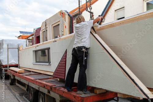 The fitter prepares the component for a prefabricated house after the truck trailer so that the crane operator can lift the part to the installation site.