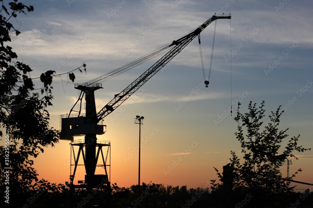 silhouette of construction cranes at sunset