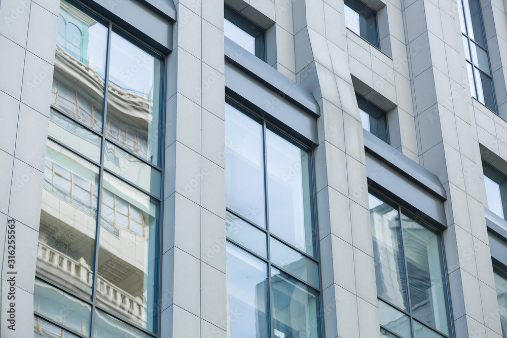 Modern architecture, building exterior. Grey wall, large windows reflecting blue cloudy sky. Office building skyscaper background Modern architecture, building exterior. Grey wall, large windows reflecting blue cloudy sky. Office building skyscaper background