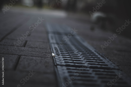 sewer grate on the asphalt. in gray tones