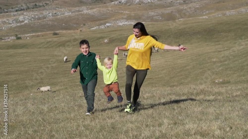 Happy family with children holding hands of each other and running through field photo