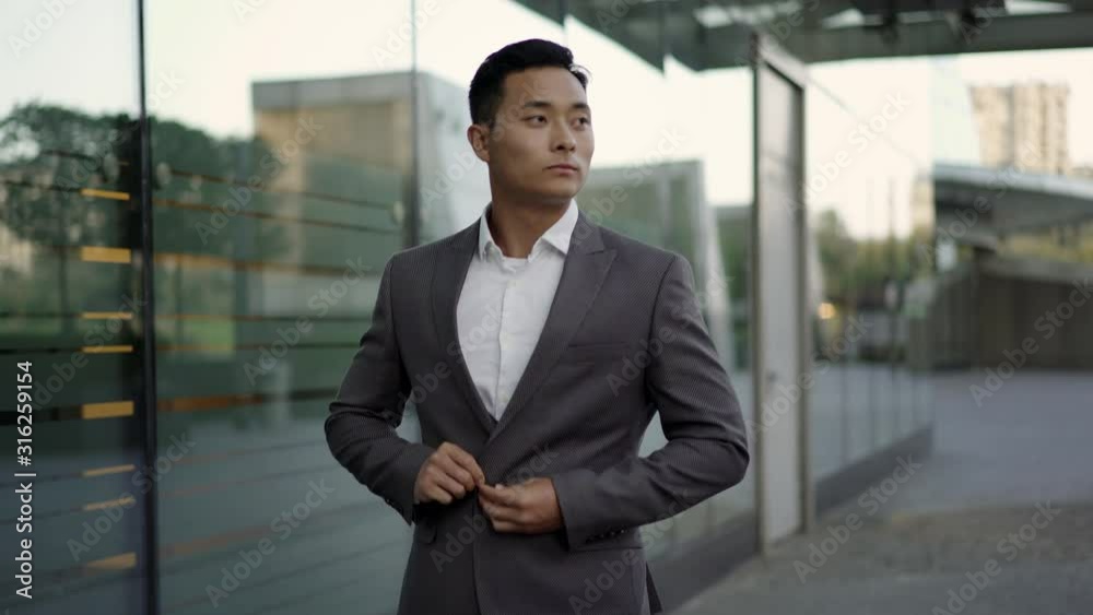 Real time portrait shot of a young businessman walking along a business building. Real time portrait shot of a young businessman walking along a business building.