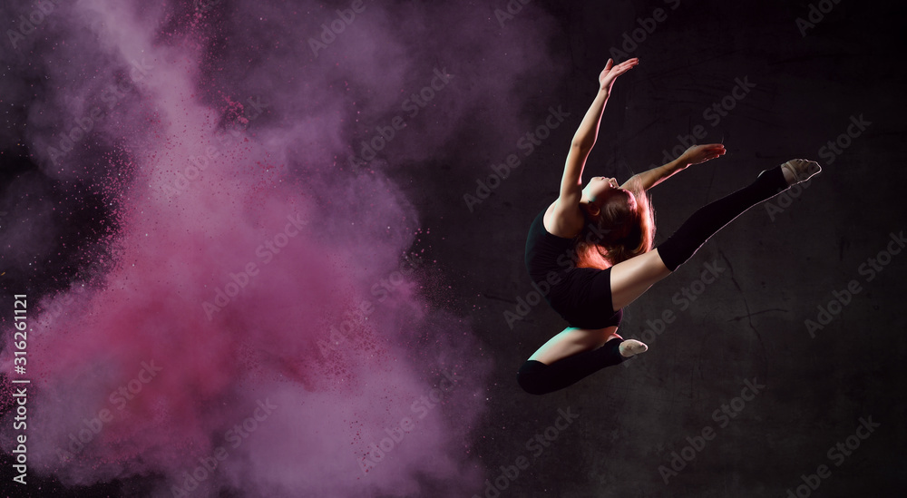 Young girl gymnast in black sport body and uppers making circle in jump over dark background with colorful glittering