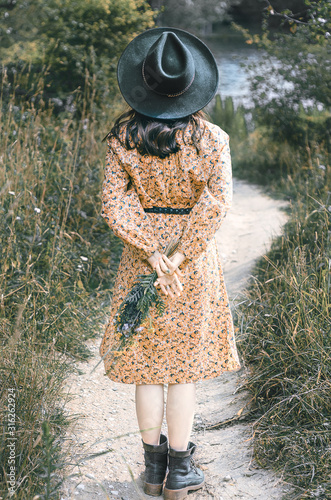 Girl in nature in a hat and with flowers. Boho style.
