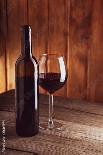 bottle of wine and a glass on old wooden table © Chepko Danil