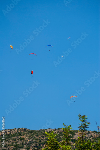 Colorful paratroopers flying over a blue sky. Image.