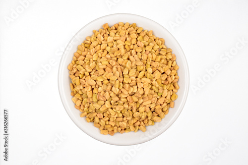 fenugreek seeds in bowl isolated on white background, top view 