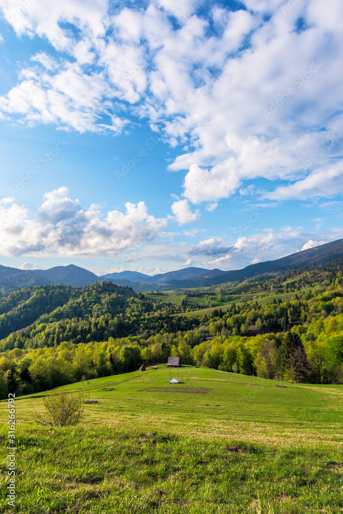 Carpathians countryside in springtime. wonderful sunny weather with dynamic cloud formations on the blue sky. forested rolling hill with rural fields in evening light. Carpathians countryside in springtime. wonderful sunny weather with dynamic cloud formations on the blue sky. forested rolling hill with rural fields in evening light.