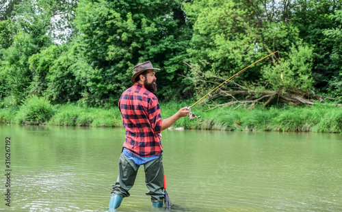 Fishing is the Reel Deal. summer weekend. Big game fishing. mature man fly fishing. man catching fish. bearded fisher in water. fisherman with fishing rod. hobby and sport activity. pothunter