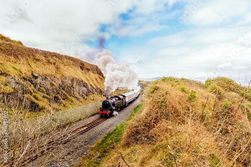 Canvas Print Large steam train or locomotive with passenger carriages on costal railway betwe