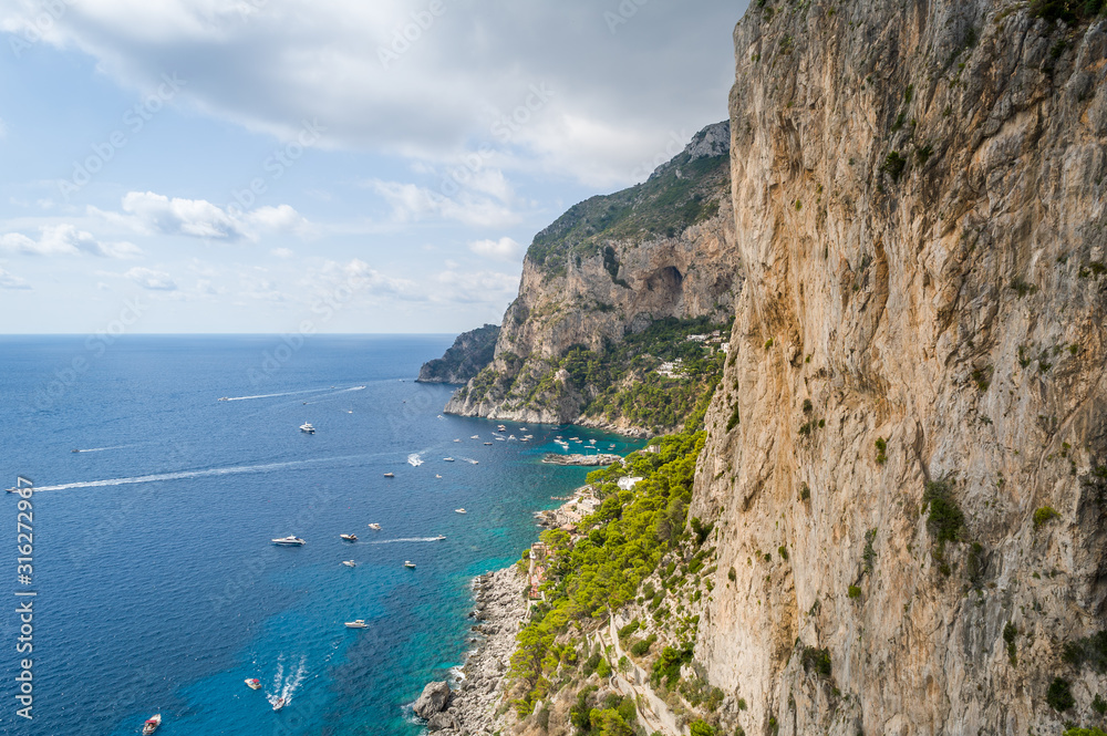 Rocks and cliffs of Capri island. Viewpoint to the sea bay with small local's boats and perfect climbing walls. Capri, Italy.