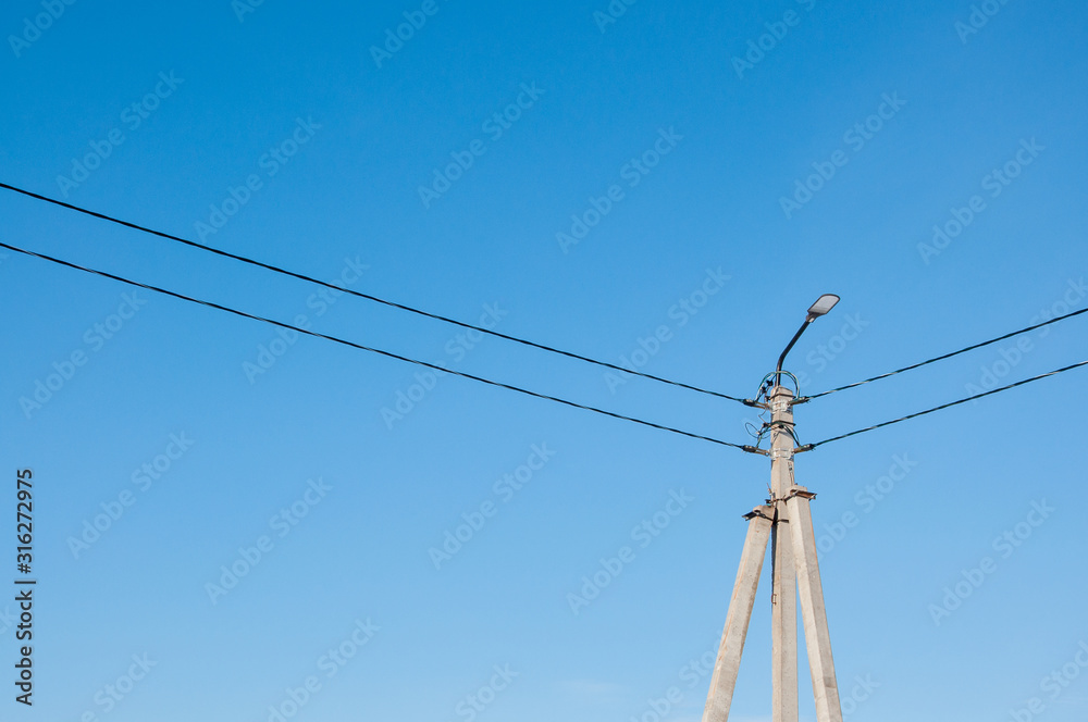 Electric pole and high voltage wires against the blue sky. Industrial landscape