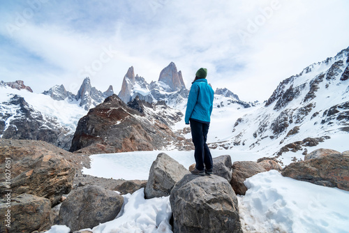A hiker woman with a blue jacket on the base of Fitz Roy Mountain in Patagonia, Argentina