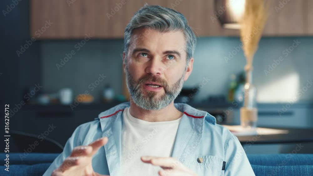 Close up portrait of european handsome middle aged man looking at camera and talking over video chat conference call recording vlog people online communication at home slow motion close up