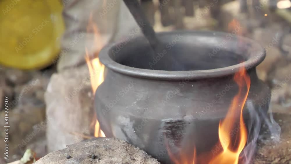 Close up shot slow motion, mixing ingredient in a clay pot on stone fire stove. Close up shot slow motion, mixing ingredient in a clay pot on stone fire stove.