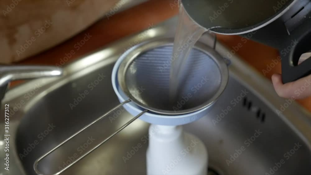Medium shot on a sink, soap mixtures pours and filter into a white plastic bottle. Medium shot on a sink, soap mixtures pours and filter into a white plastic bottle.
