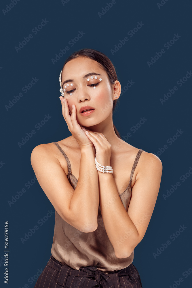 Freestyle. Young woman eyes decorated with perls standing isolated on dark blue posing to camera lips opened sensual Freestyle. Young woman eyes decorated with perls standing isolated on dark blue posing to camera lips opened sensual