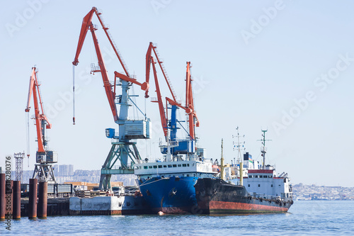 Panorama of the cargo seaport. In the water area of the port there are ships for unloading and loading and port cranes.