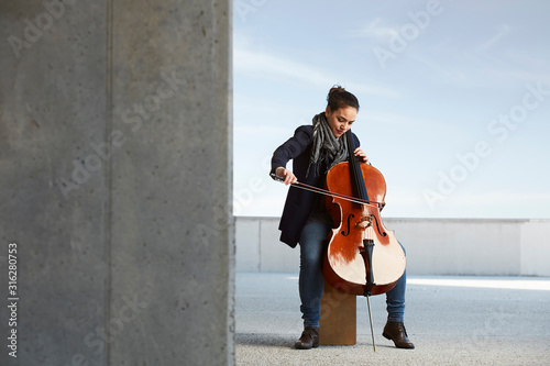 Foto beautiful girl plays the cello with passion in a concrete environment