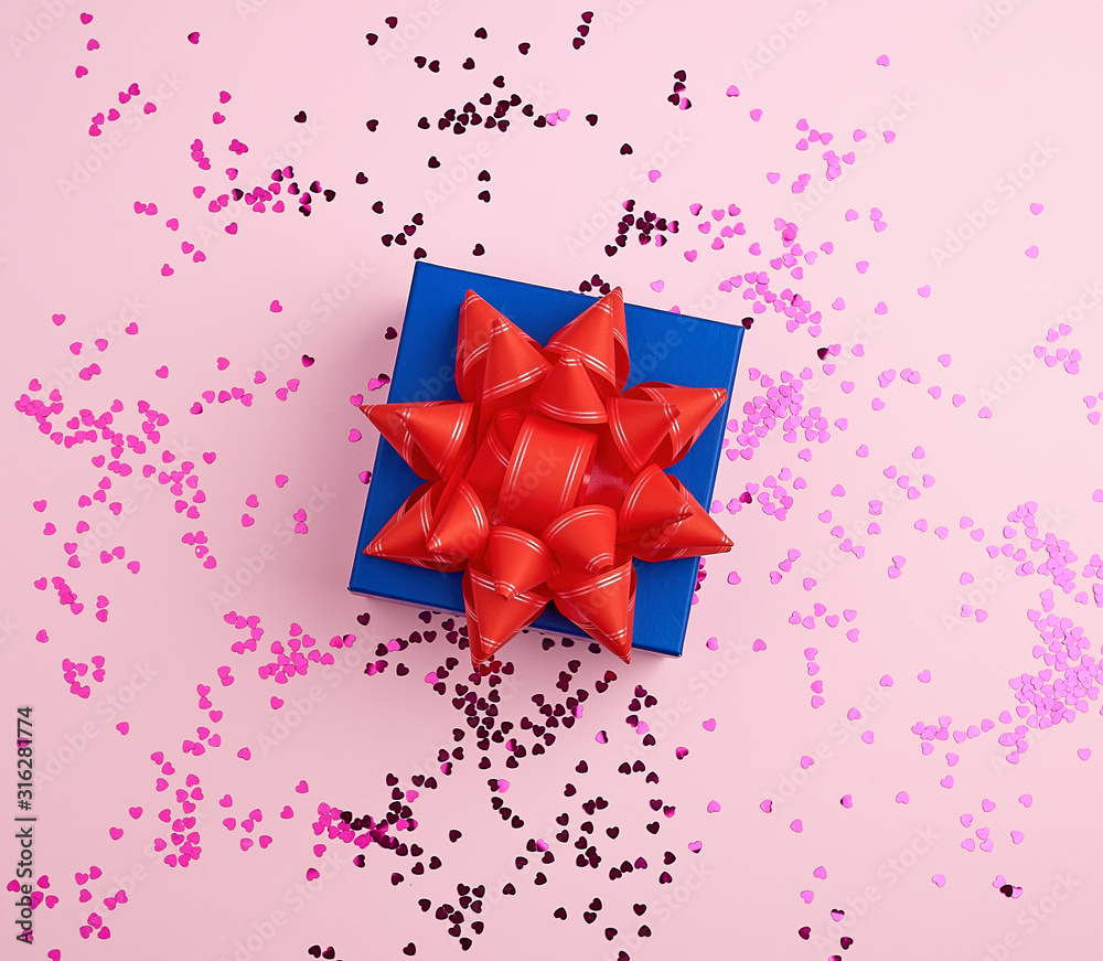 closed square blue gift box with red bow on a pink background closed square blue gift box with red bow on a pink background