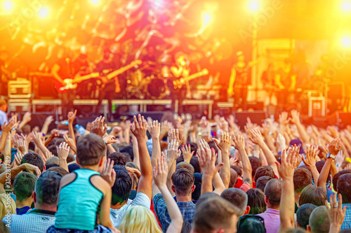 Fans and crowd of fans at a rock music concert in the evening outdoors.