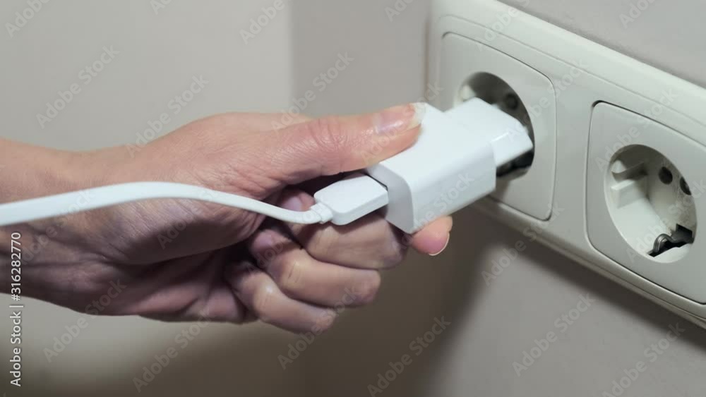 close-up woman hand puts plug in the Electricity socket. Female hand unplugging close-up woman hand puts plug in the Electricity socket. Female hand unplugging