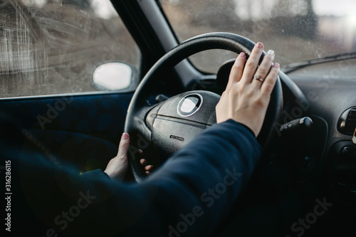 Female hands of the driver on the steering wheel while riding.