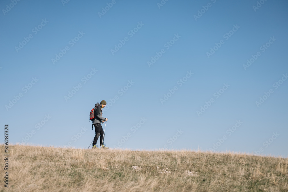 Young man walking on a hill with blue heavens