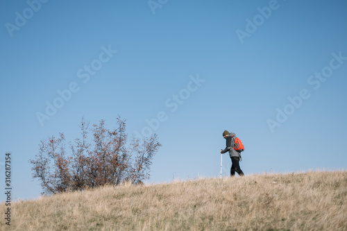 Man walking through field against blue sky