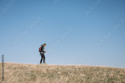 Young man walking on a hill with blue heavens