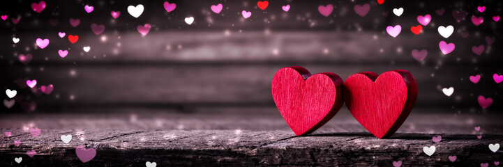 Two Wooden Hearts On Rustic Table With Colorful Heart Shaped Bokeh - Valentine's Day Concept