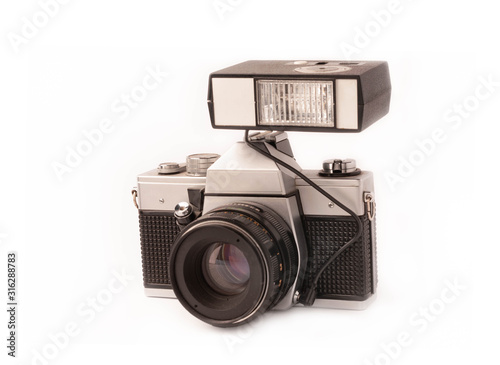 retro old manual mechanical camera with external flash and metal lens isolated on white