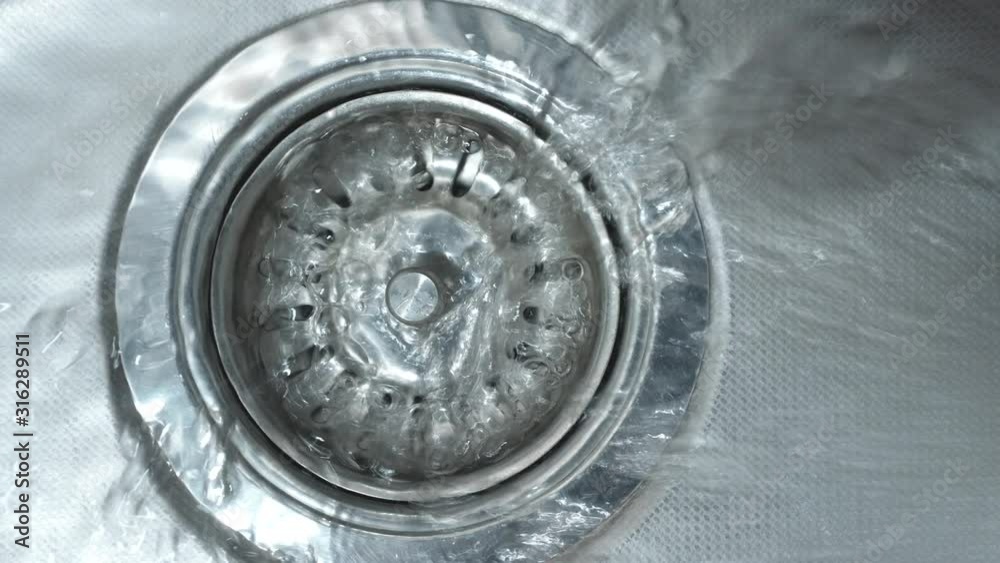 Streaming water in sink. Water stream going down the drain. Streaming water in sink. Water stream going down the drain.
