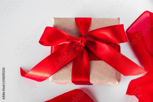 Gift box with craft paper and red ribbon on a white background