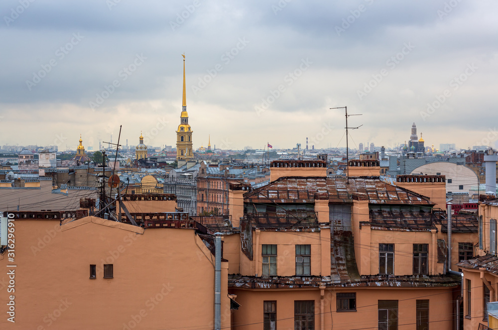 Beautiful top view of the historic city center of St. Petersburg. Cityscape with roofs of buildings and a high bell tower of the Peter and Paul Cathedral with a golden spire. Saint-Petersburg, Russia.