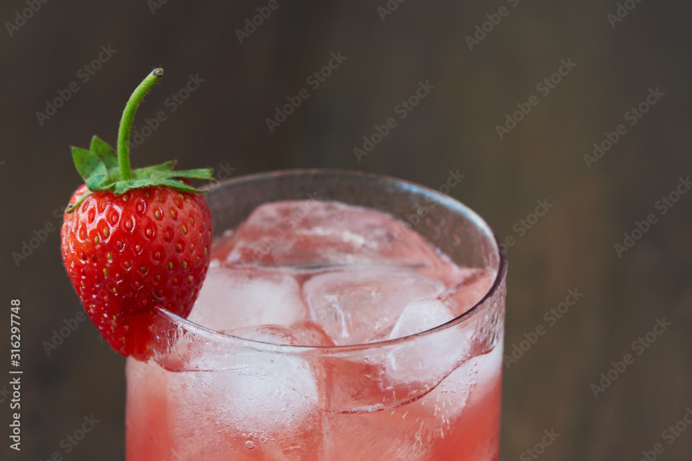 A glass of tasty cold strawberry juice with ice on the table. A glass of tasty cold strawberry juice with ice on the table.