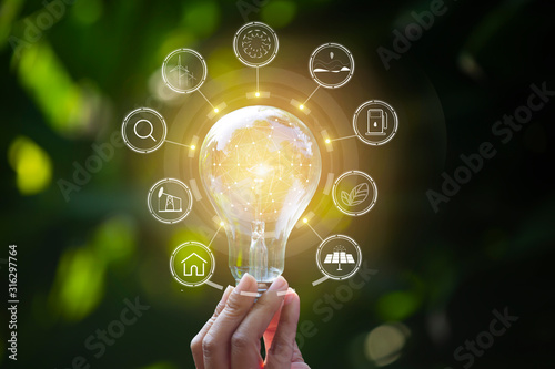 hand holding light bulb against nature, icons energy sources for renewable,