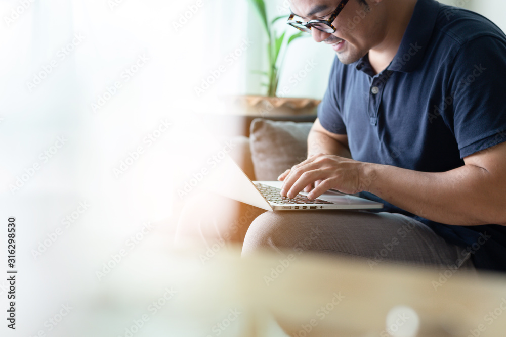 using computer.asian man hand typing message keyboard laptop shopping online.search information form internet while sitting on sofa.concept use technology device contact communication business - obrazy, fototapety, plakaty 