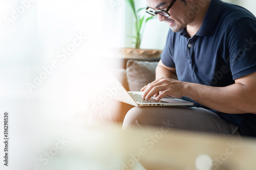 using computer.asian man hand typing message keyboard laptop shopping online.search information form internet while sitting on sofa.concept use technology device contact communication business