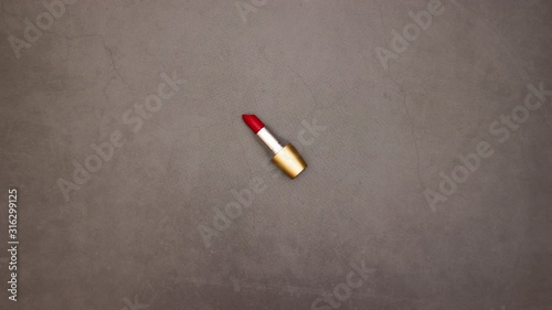 Red trendy lipstick come fast and spin in circle on dark background - Stop motion  photo