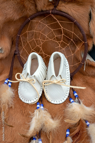 Native American photograph featuring baby leather moccasins, a dream catcher and a rabbit pelt with bokeh effect.