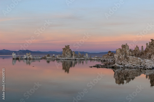 tufa formations and pink sunrise reflecting in still Mono Lake