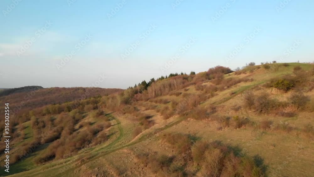Drone flying over a hill towards trees in a rural area in Romania Drone flying over a hill towards trees in a rural area in Romania